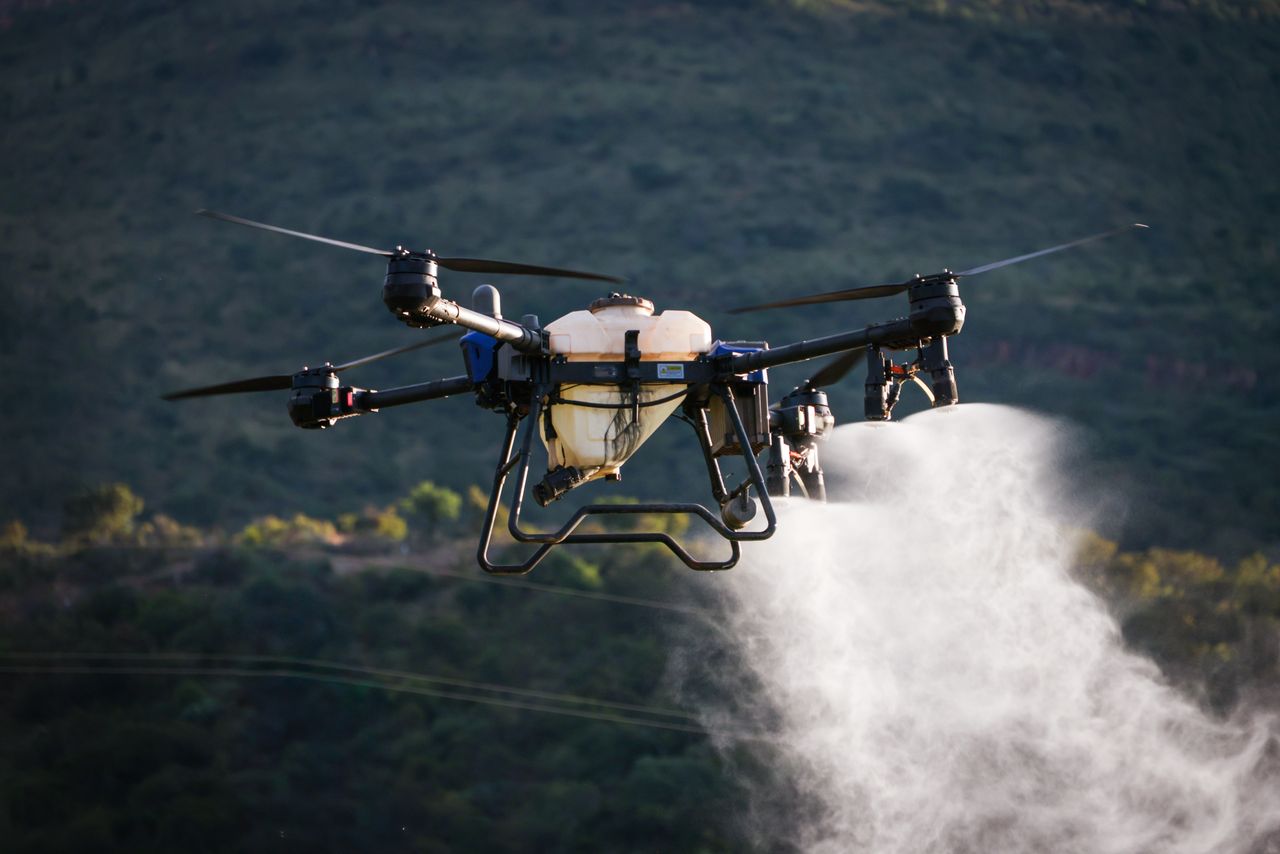 A drone disperses chemicals over crops in an agricultural field, enhancing productivity.